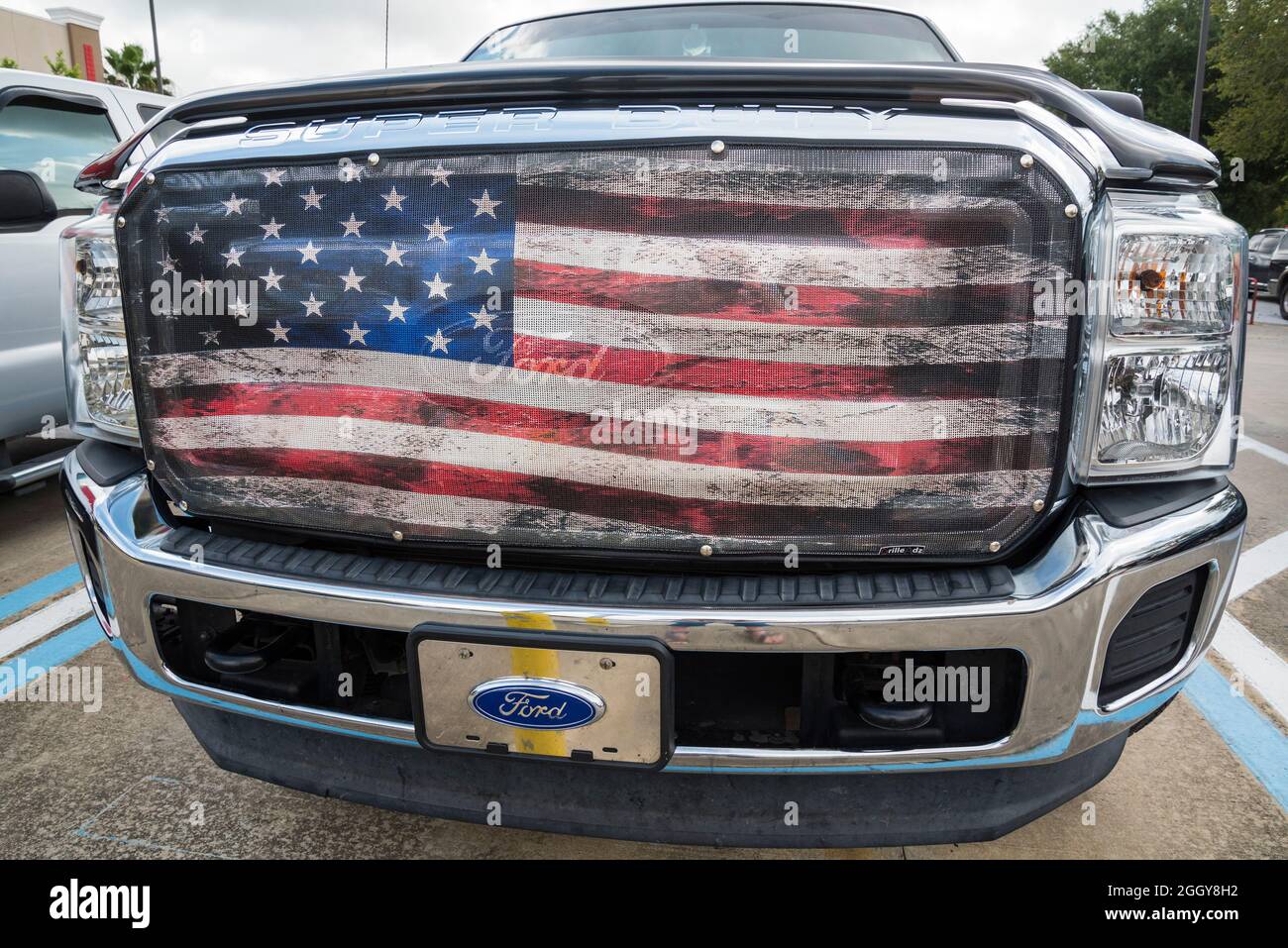 Pickup-Truck mit einer riesigen amerikanischen Flagge in den Kühlergrill eingebettet. Stockfoto