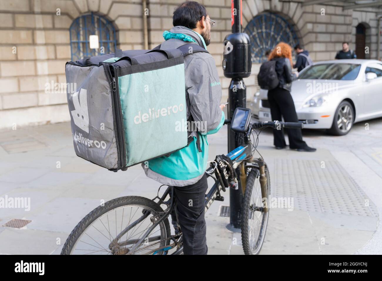 Deliveroo Bike Rider und seine Hintertasche warten an der Fußgängerüberfahrt Bank Junction London England Stockfoto