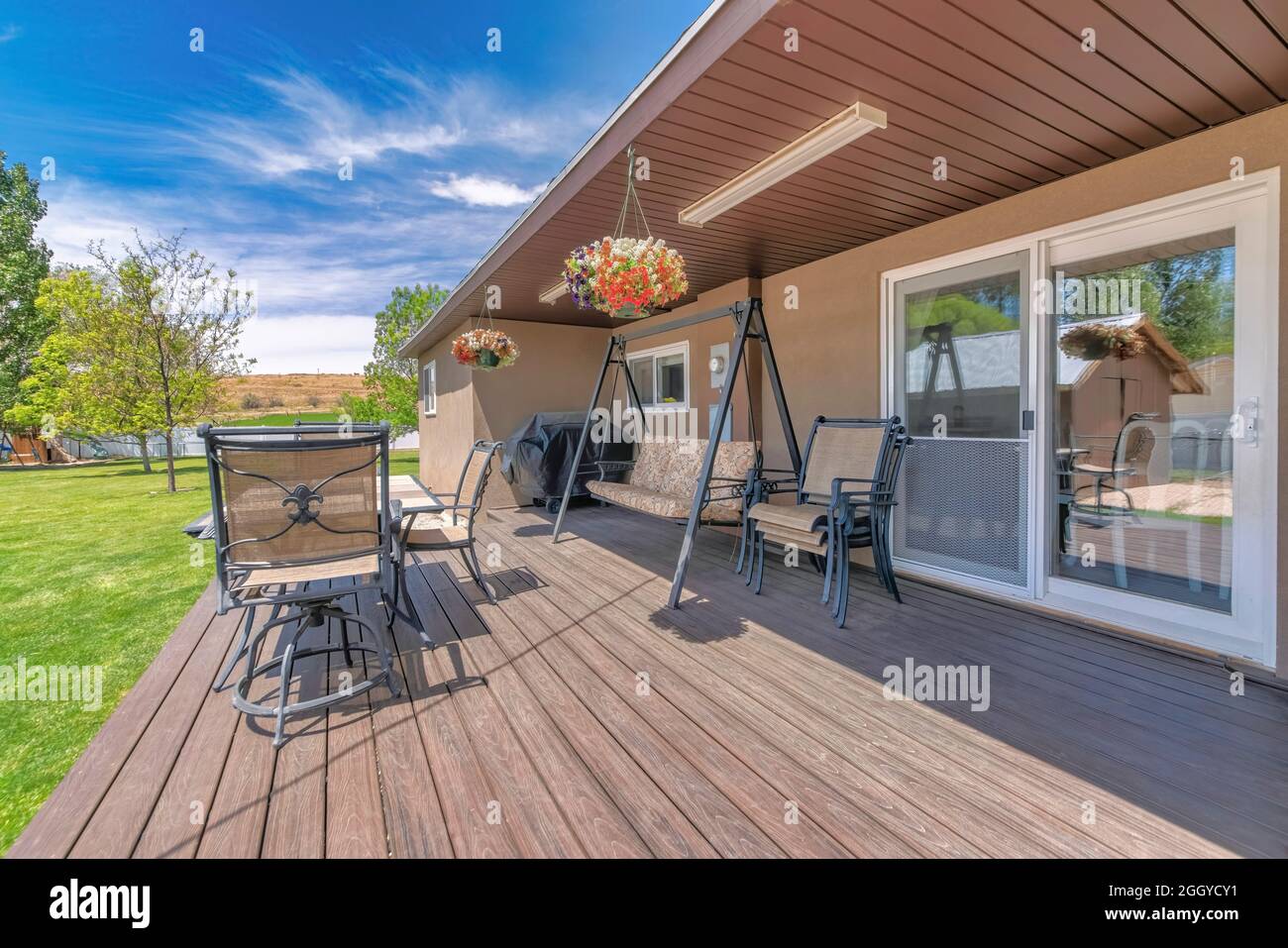 Terrasse im Freien mit überdachtem Grill, Holzboden und Liegestühlen Stockfoto