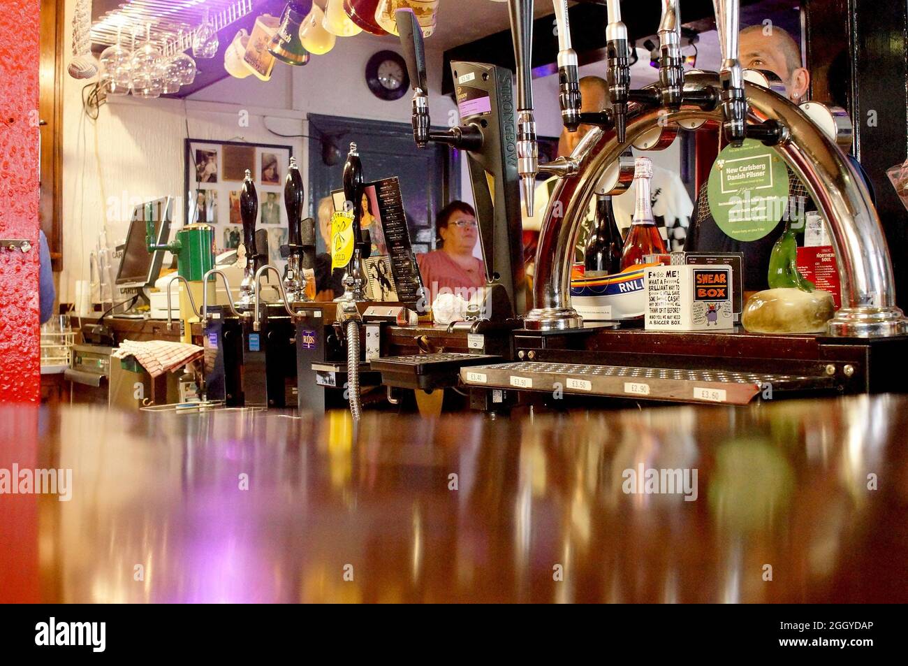 Hinter einer Bar in einem traditionellen englischen Pub mit Menschen im Hintergrund Stockfoto