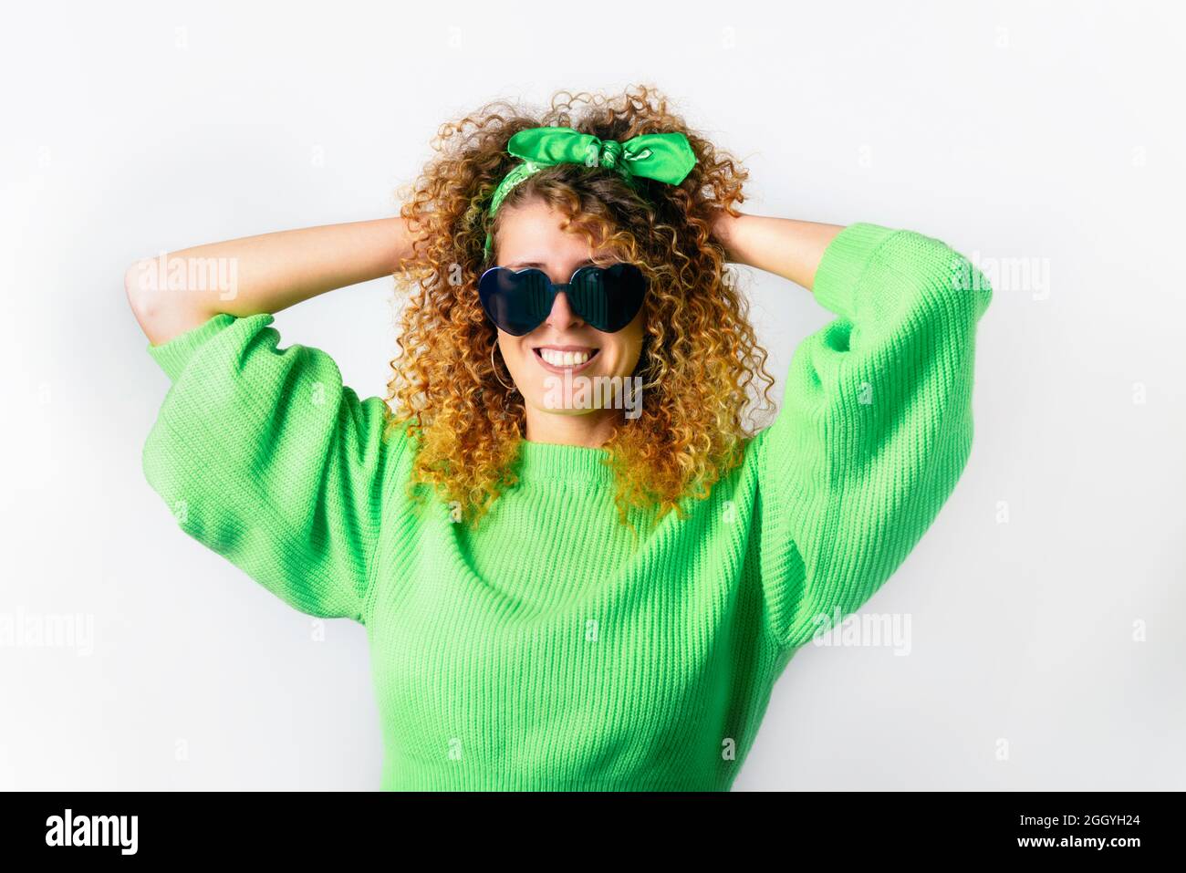 Porträt einer glücklichen lächelnden Frau in einem leuchtend grünen  Pullover und herzförmiger Sonnenbrille auf weißem Hintergrund. Liebe,  Gefühle ausdrücken, positive Gesichtsbehandlung Stockfotografie - Alamy