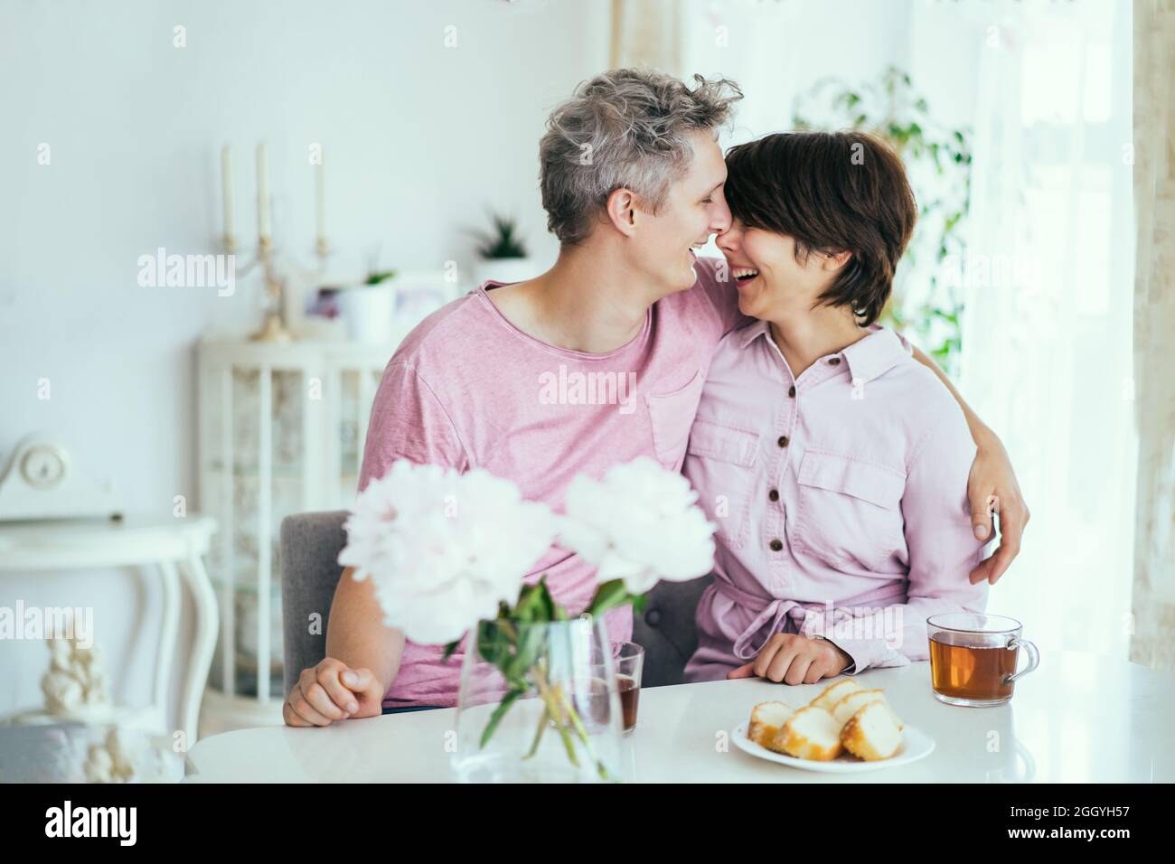 Lachendes Paar verliebt sich beim Frühstück in der Küche zu Hause. Umarmungen und Küsse. Glückliche Momente. Zeit mit der Familie. Selektiver Fokus. Stockfoto