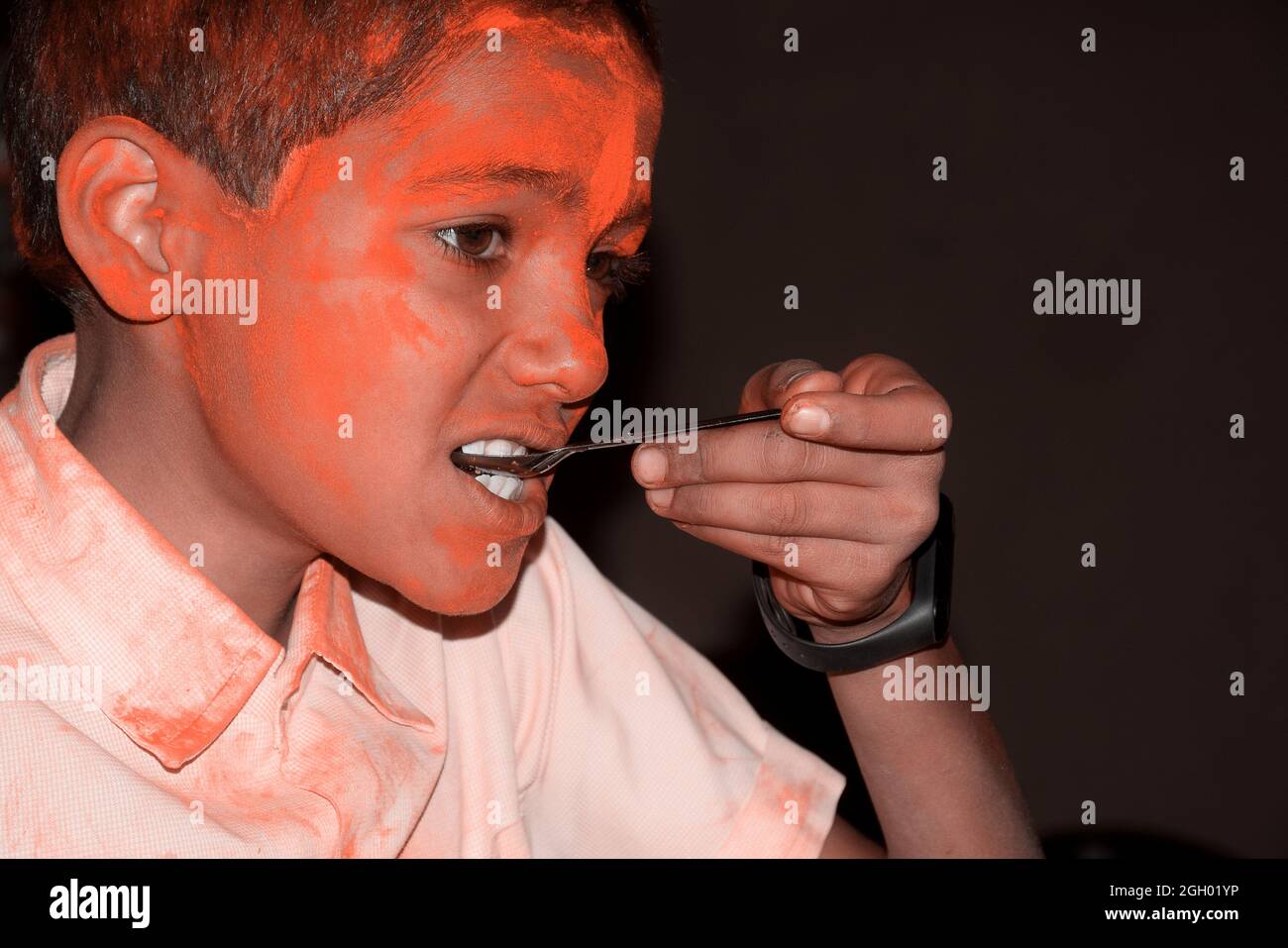 Junge mit buntem Gesicht beim Frühstück. Konzept für das indische Festival Holi Stockfoto