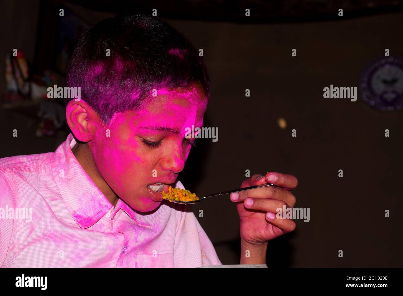 Junge mit buntem Gesicht beim Frühstück. Konzept für das indische Festival Holi Stockfoto