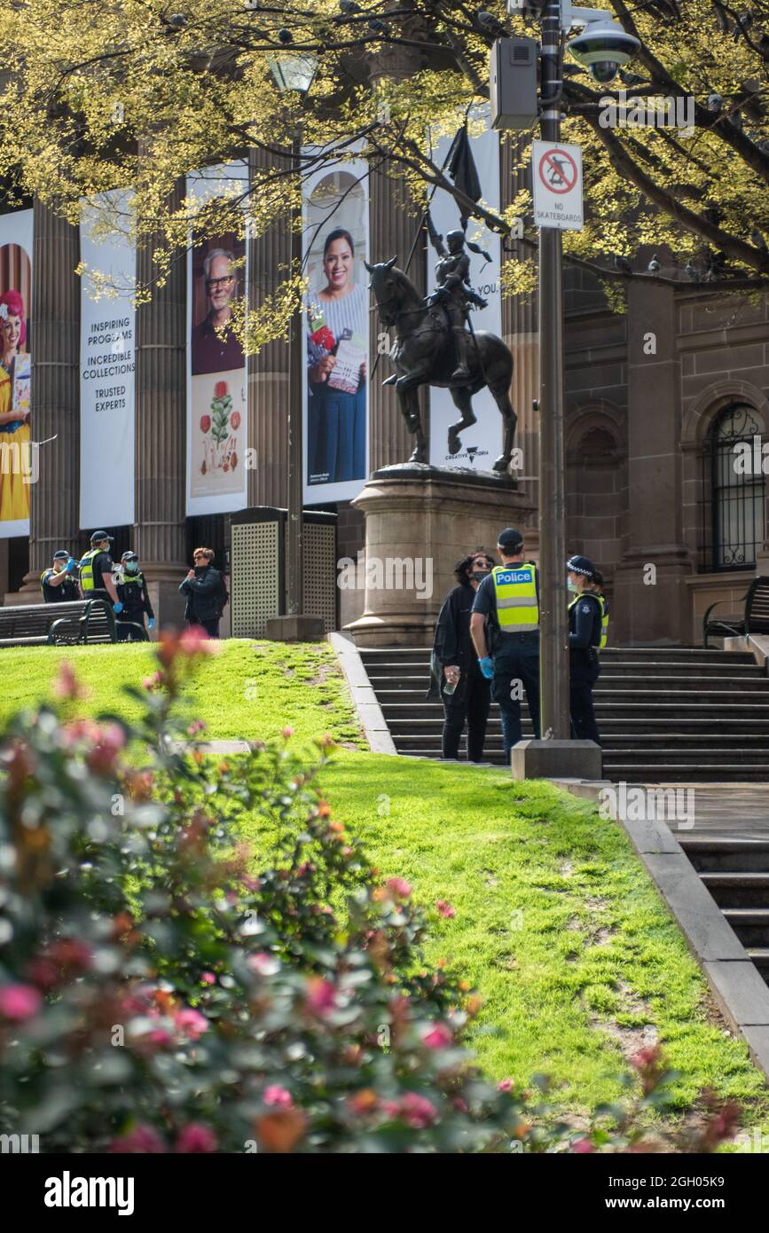 Melbourne, Australien. September 2021. Die Polizei stellt Anti-Lockdown-Demonstranten unter einer Statue von Jeanne d'Arc vor der Staatsbibliothek in Frage, wo ein Anti-Lockdown-Protest nicht mobilisiert werden konnte. Quelle: Jay Kogler/Alamy Live News Stockfoto