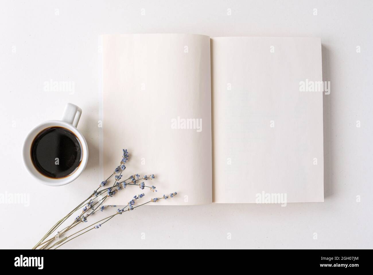 Geöffneter Notizblock, Buch mit weißen leeren Blättern auf einem Schreibtisch. Heißer schwarzer Kaffee, trockenes Lavendelbukett. Morgenstimmung, Platz für Text Stockfoto