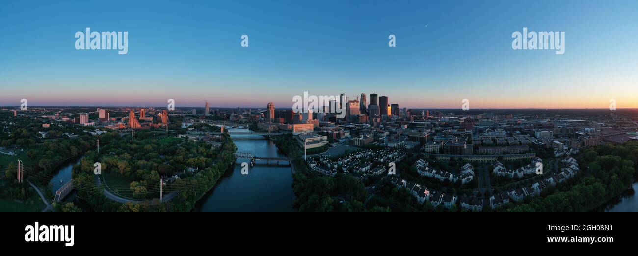 Der Sonnenuntergang kommt zum Flussufer und in der Innenstadt der nördlichen Stadt Minneapolis MN in einem langen Panorama Stockfoto