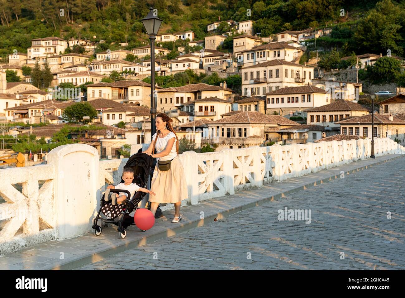 Mutter mit Kind in einem Kinderwagen, der eine traditionelle Brücke in einem alten Teil der unesco-Stadt berat albanien überquert Stockfoto