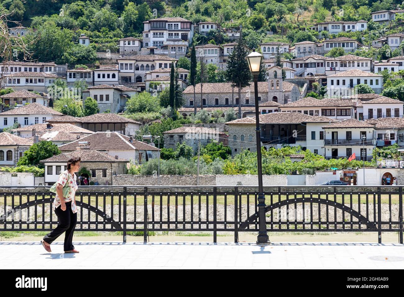 Eine Dame, die auf einem Bürgersteig in einem alten Teil der Stadt berat in albanien spazierengeht Stockfoto
