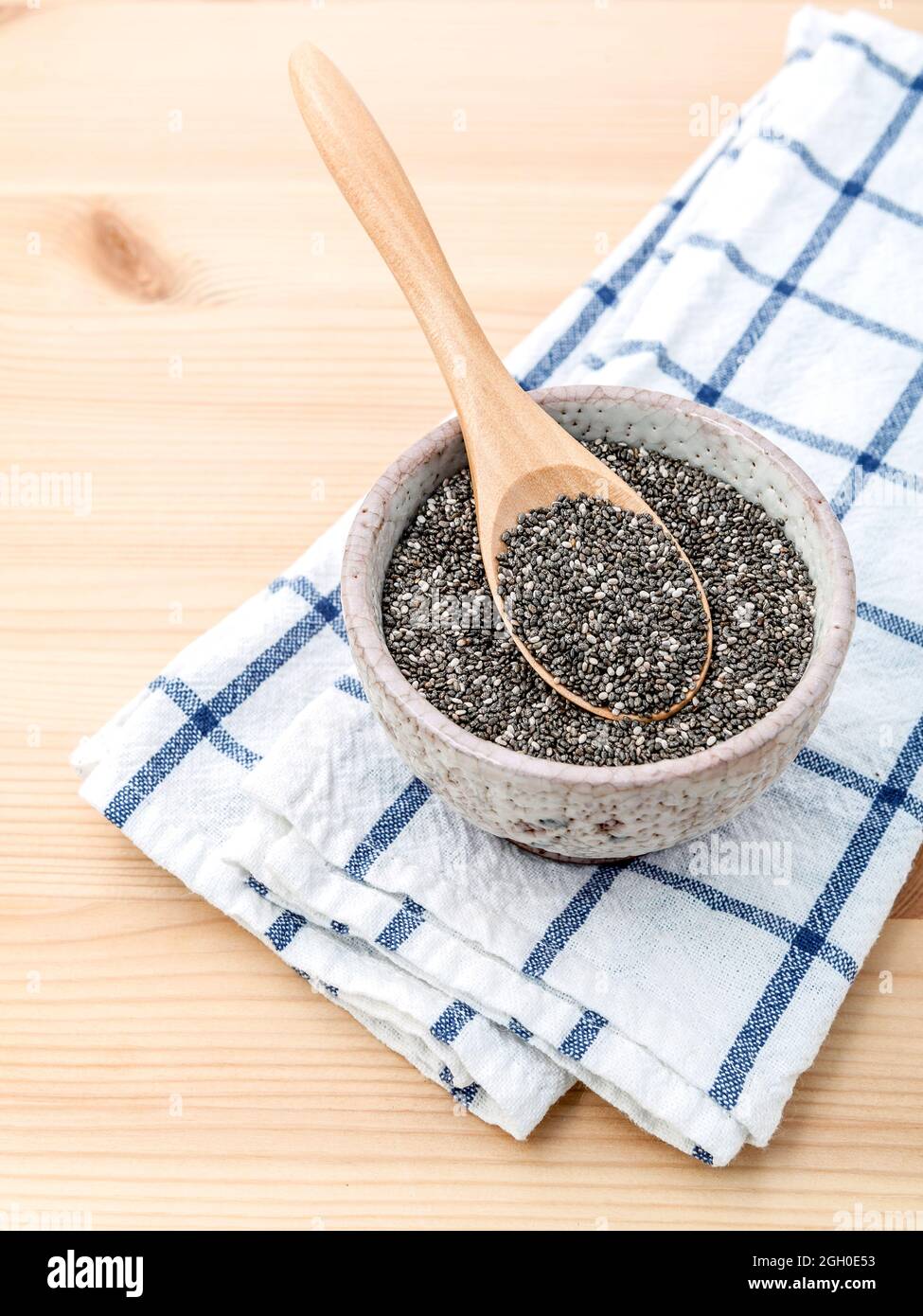 Nahrhafte Chia Samen in Keramik Schüssel mit Löffel aus Holz für Ernährung Lebensmittel Zutaten. Stockfoto