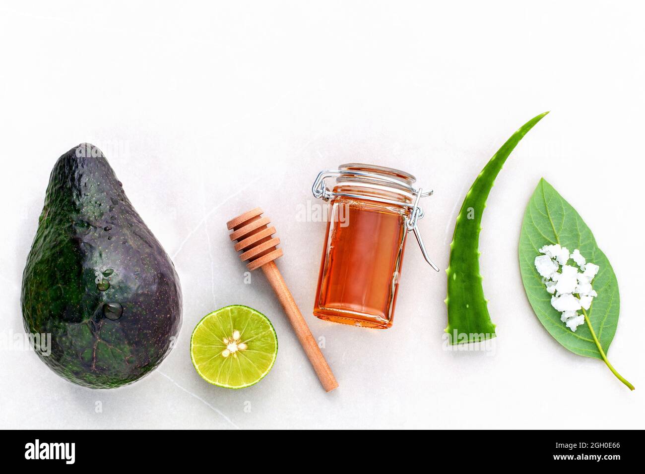Alternative Pflege und scheuern Sie frischen Avocado, Blätter, Meersalz, Öle, Kalk und Honig auf Marmor Hintergrund. Stockfoto