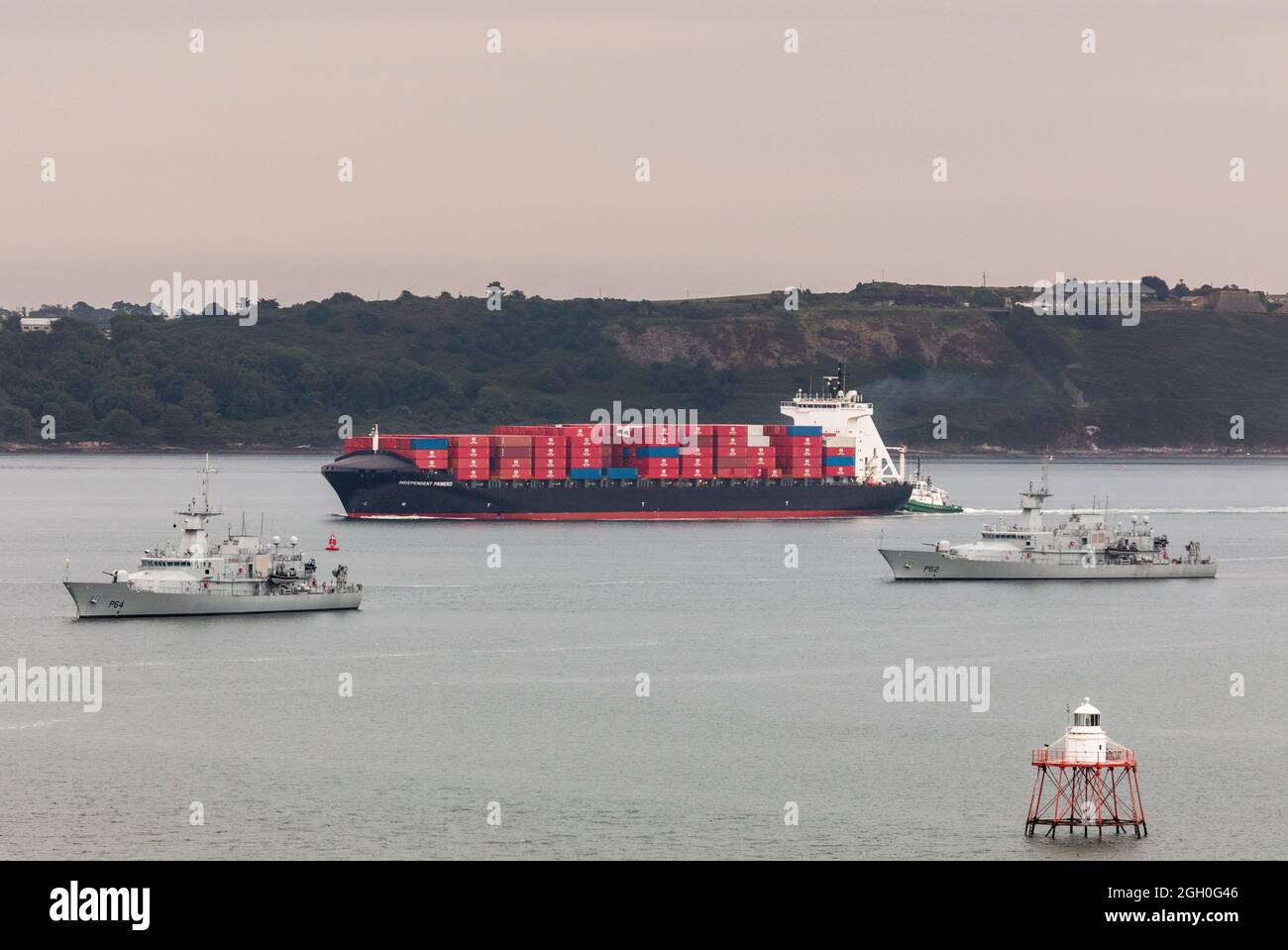 Cobh, Cork, Irland. September 2021. Das Containerschiff Independent Primero kommt im Hafen von Cork an, um eine Frachtbount für Amerika abzuholen, während das Marineschiff LÉ LÉ George Bernard Shaw (P64) und LÉ James Joyce (P62) vor Anker liegen in Cobh, Co. Cork, Irland. - Bild; - David Creedon Credit: David Creedon/Alamy Live News Stockfoto