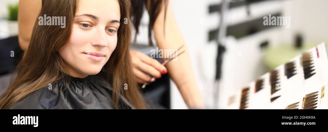 Frau im Schönheitssalon wählt Haarfärbefarbe aus dem Katalog Stockfoto