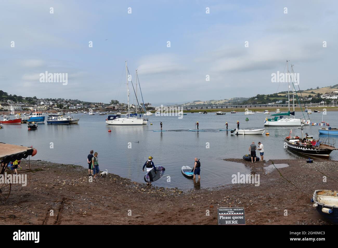 Teignmouth Back Beach und Teignmouth Harbour. Das ist tagsüber mit Booten und Paddelboardern auf dem Wasser lebendig. Die Nacht ist zum Tanzen. Stockfoto