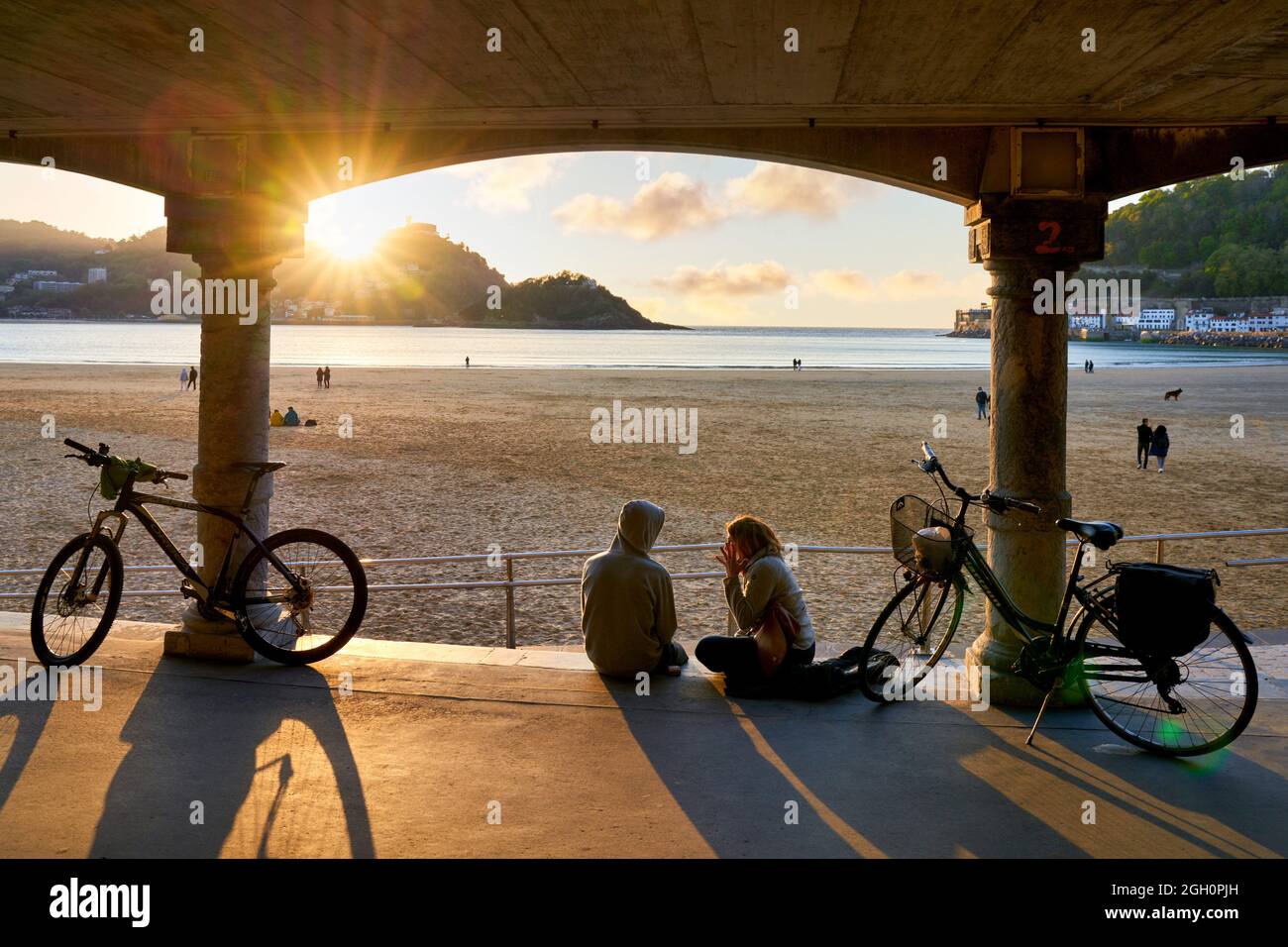 Paar mit ihren Fahrrädern, Sonnenuntergang am La Concha Strand, Donostiarra Juwel par excellence, Emblem der Stadt, unvergleichliche Umgebung, Es befindet sich in Stockfoto