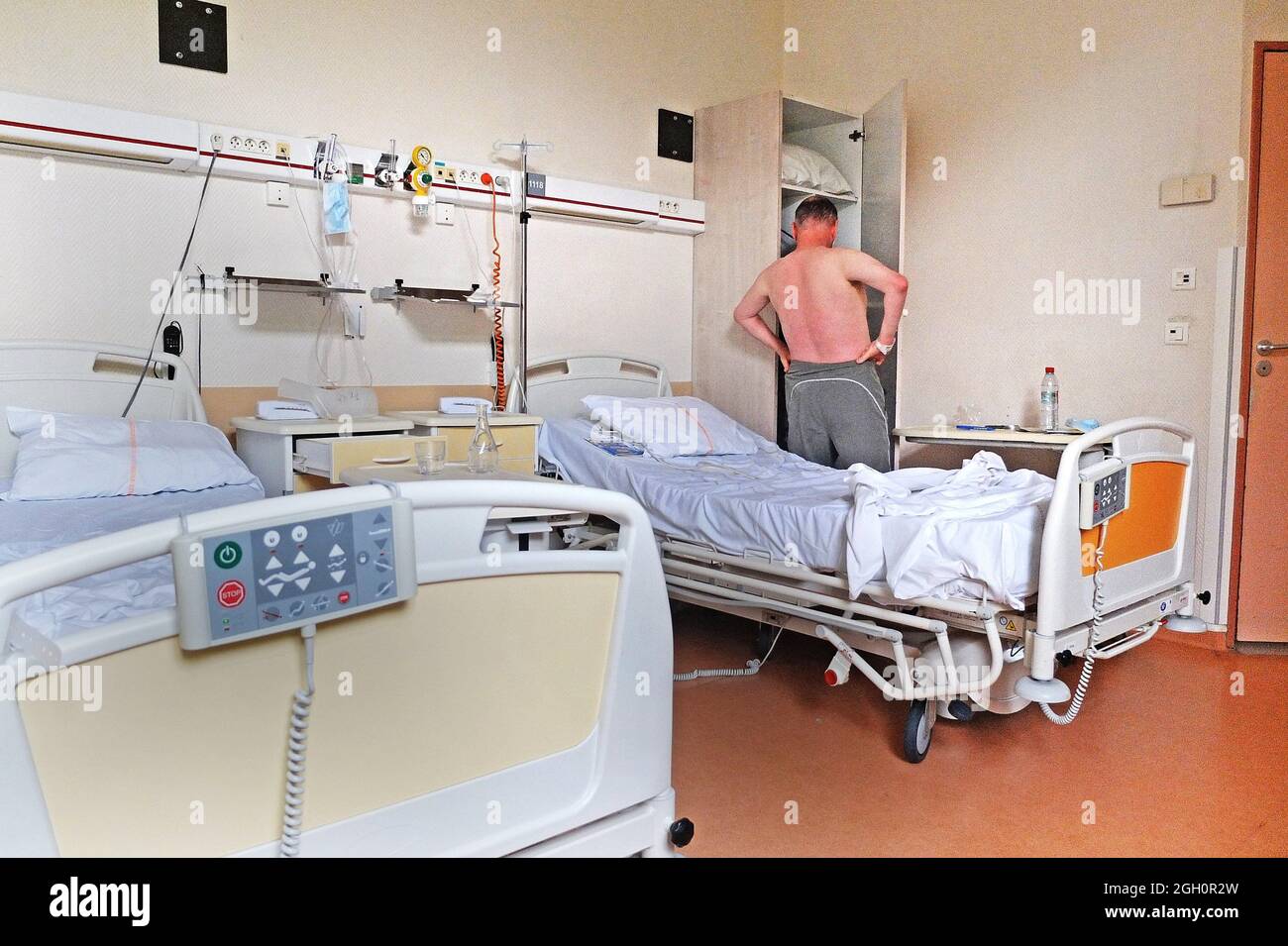Ein Patient in einem Krankenhauszimmer, der sich für die Entlassung kleidet. Stockfoto