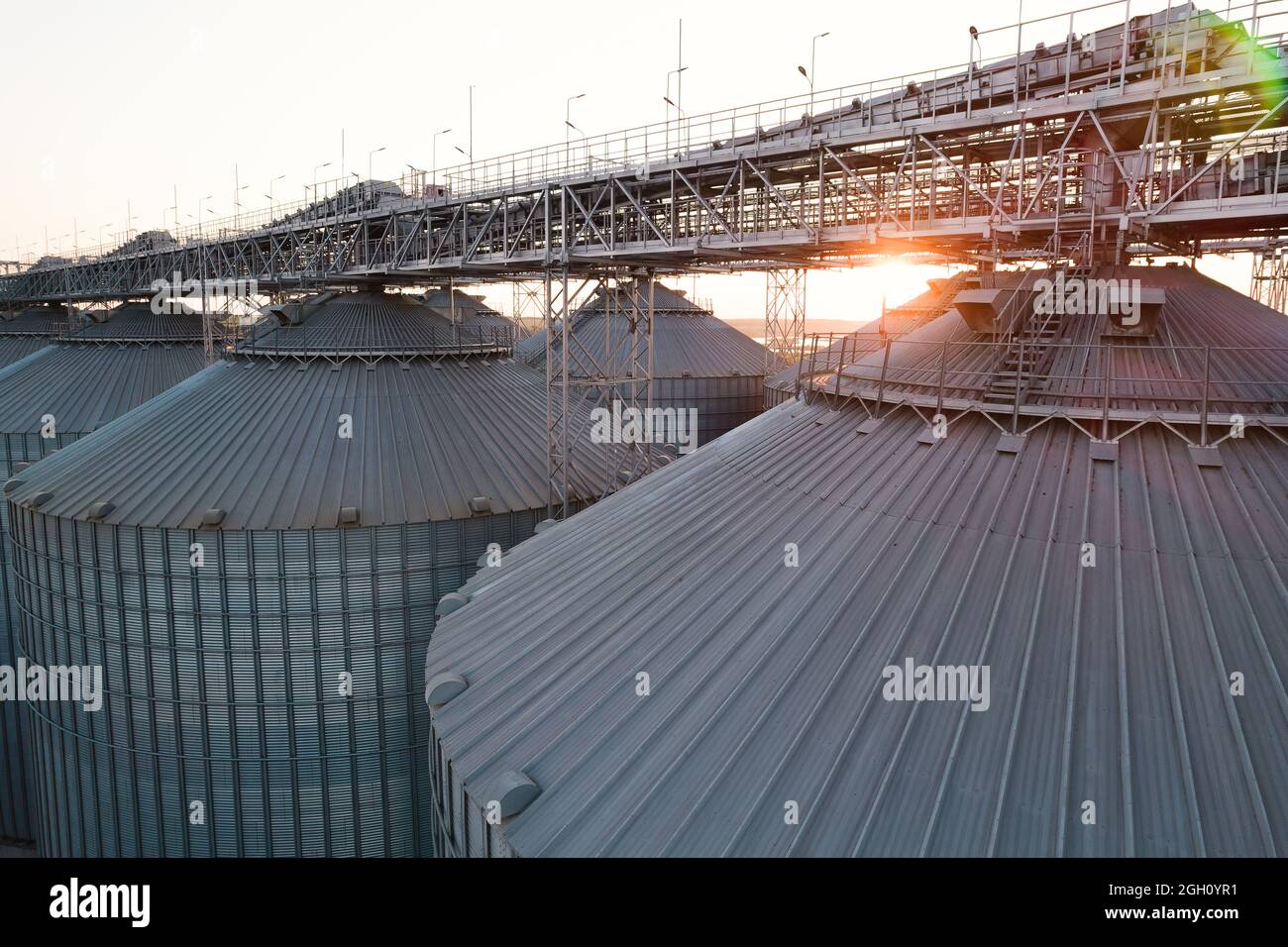 Getreideterminals des modernen Handelshafens. Silos zur Lagerung von Getreide in Strahlen untergehenden Sonnenlichtes, Draufsicht vom Quadcopter. Industrieller Hintergrund. Logist Stockfoto