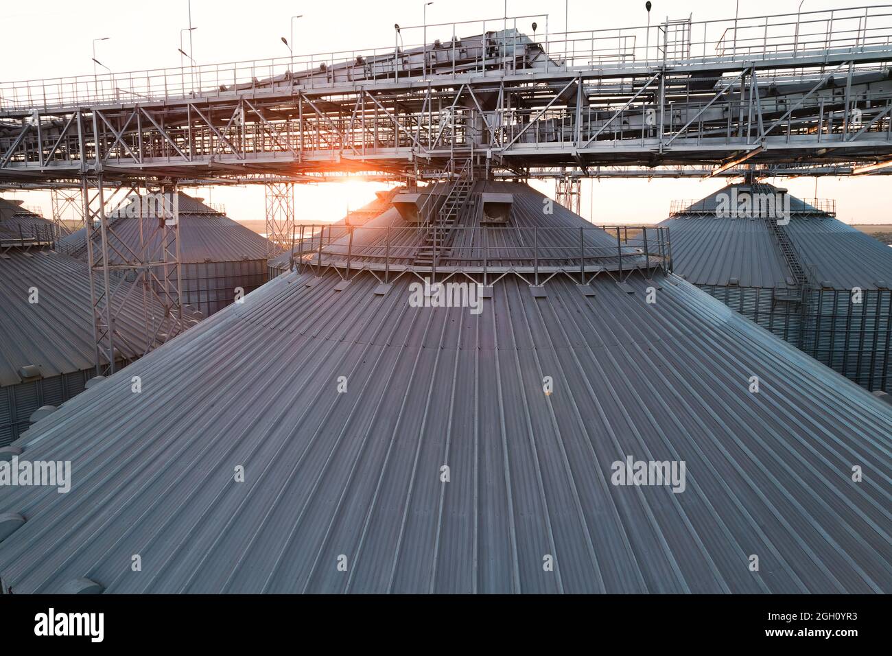 Getreideterminals des modernen Handelshafens. Silos zur Lagerung von Getreide in Strahlen untergehenden Sonnenlichtes, Draufsicht vom Quadcopter. Industrieller Hintergrund. Logist Stockfoto