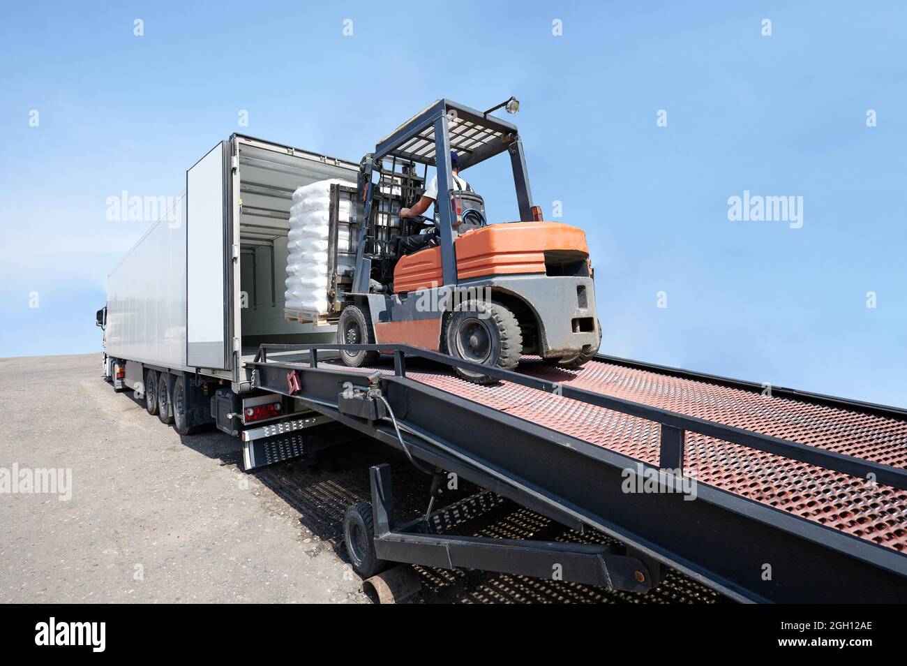 Gabelstaplerladerpalette mit Ladung zu LKW isoliert auf blauem Himmel Hintergrund Stockfoto