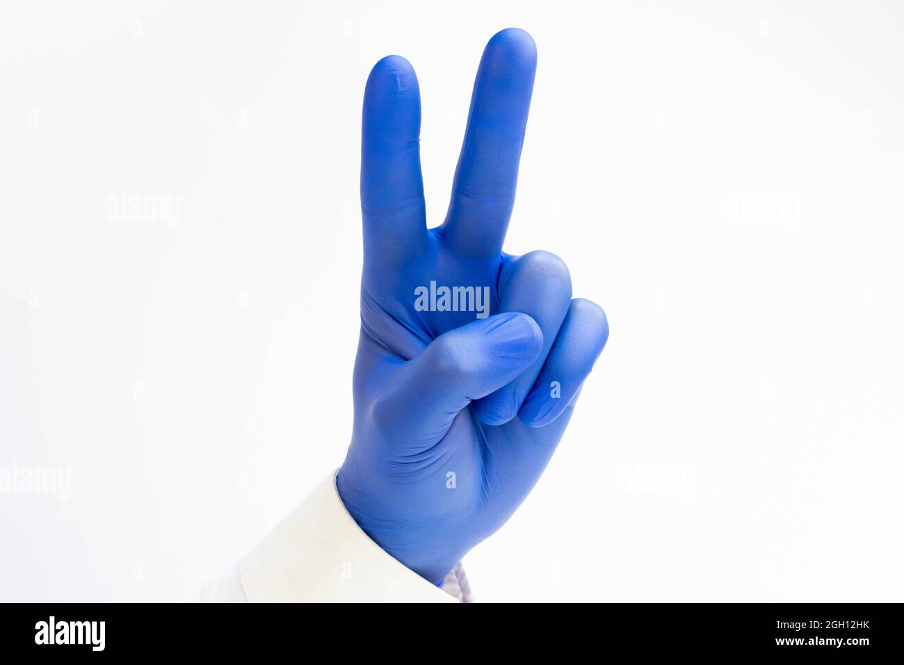 Hand in blauem Latex Handschuh, der zwei Finger auf der Hand hochhebt, zeigt Frieden Stärke Kampf oder Sieg Symbol. Stockfoto