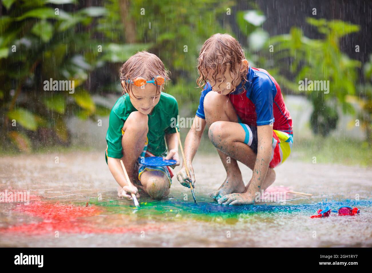Kinder spielen im Regen. Kreidezeichnen Spaß. Kunst und Kunsthandwerk für  kleine Kinder. Jungen experimentieren mit Aquarell in schwerer Dusche im  Freien im Garten Stockfotografie - Alamy