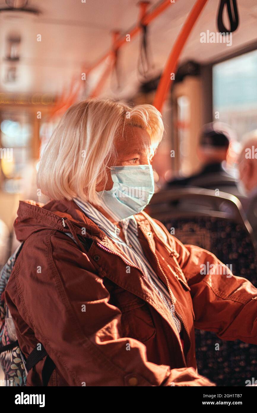 Frau mit chirurgischer Schutzmaske in öffentlichen Verkehrsmitteln Stockfoto