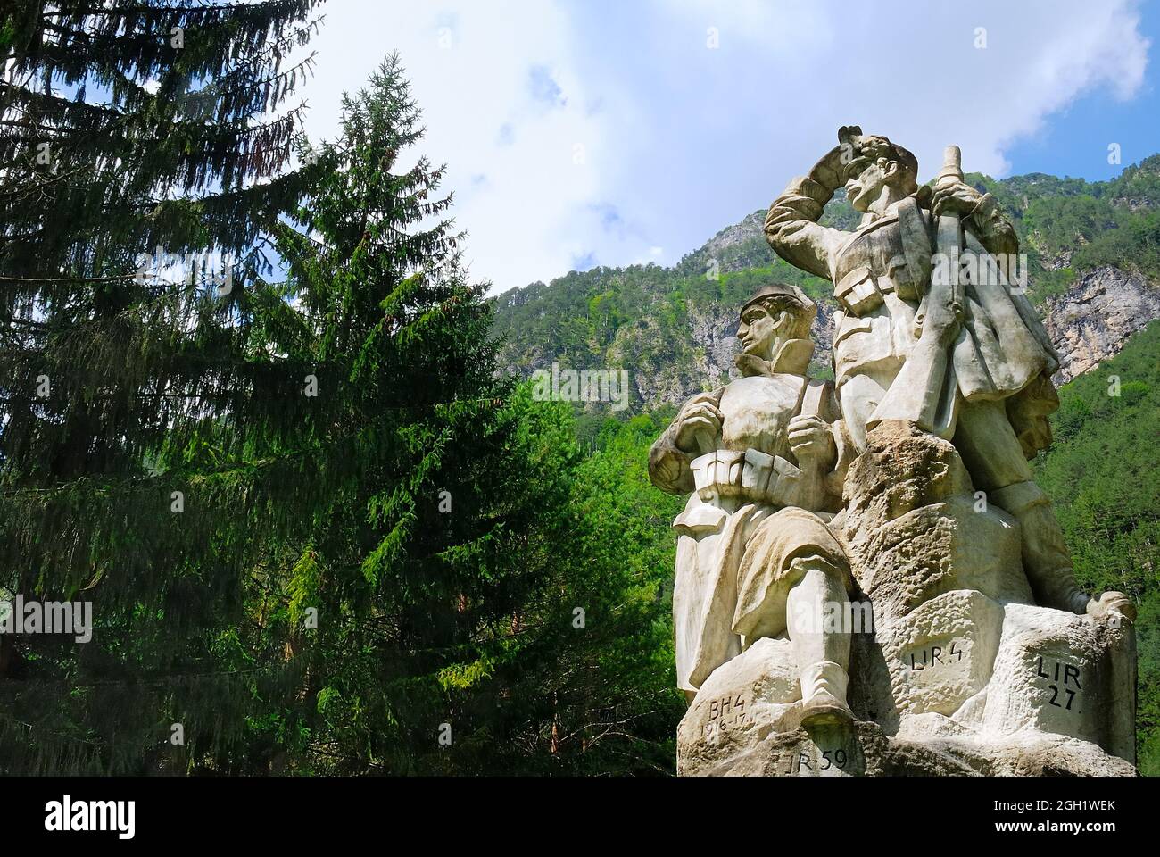 Slowenien, Log pod Mangartom. WWI. Das beeindruckende Denkmal, das in der Mitte des großen österreichisch-ungarischen Kriegsfriedhofs steht. Es wurde zum Gedenken an die Soldaten des Berges Rombon errichtet, realisiert vom Prager Künstler Ladislav Kofanek. Es stellt einen bosnischen Soldaten mit fes und einen österreichischen Soldaten mit Kaiserschutzencap dar. Die Abkürzung BH4 steht für 4. Regiment Bosnien-Herzegowina, während LIR für Lands Imperial Regiment steht. Beide sind vertreten und blicken auf den nahegelegenen Rombon. Stockfoto