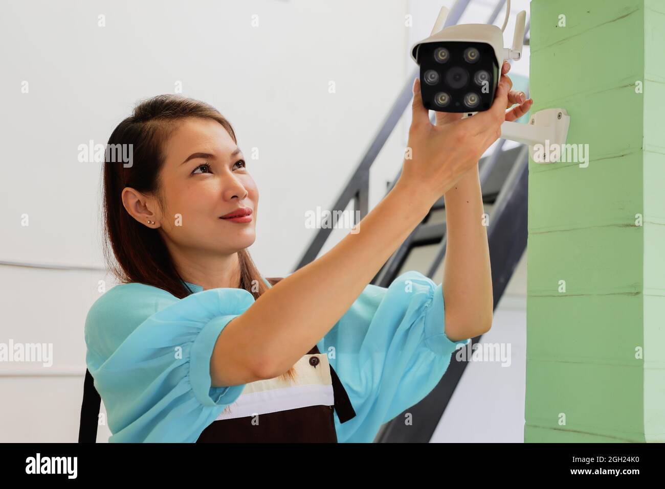 Schöne Frau Haus passt die Richtung Winkel Ansicht der CCTV-Überwachungskamera und Feinabstimmung Internet-Kamera für die perfekte Szene zu beobachten. Konept für s Stockfoto