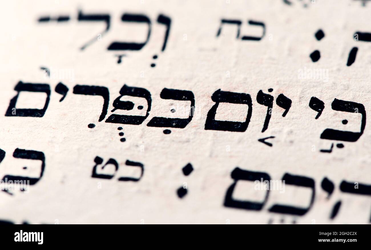 Nahaufnahme der hebräischen Wörter Yom Kippur auf der Tora-Seite, die auf englisch als Versöhnungstag, heiligster Tag des Jahres im Judentum, übersetzt werden. Selektiver Fokus Stockfoto