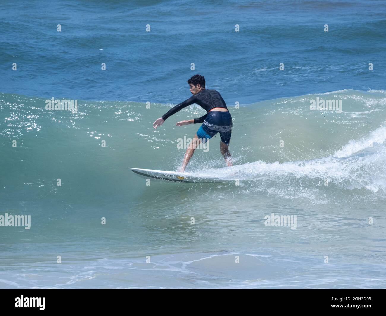 Surfer nehmen Wellen und manövrieren am Meer an einem klaren Sommertag. Stockfoto