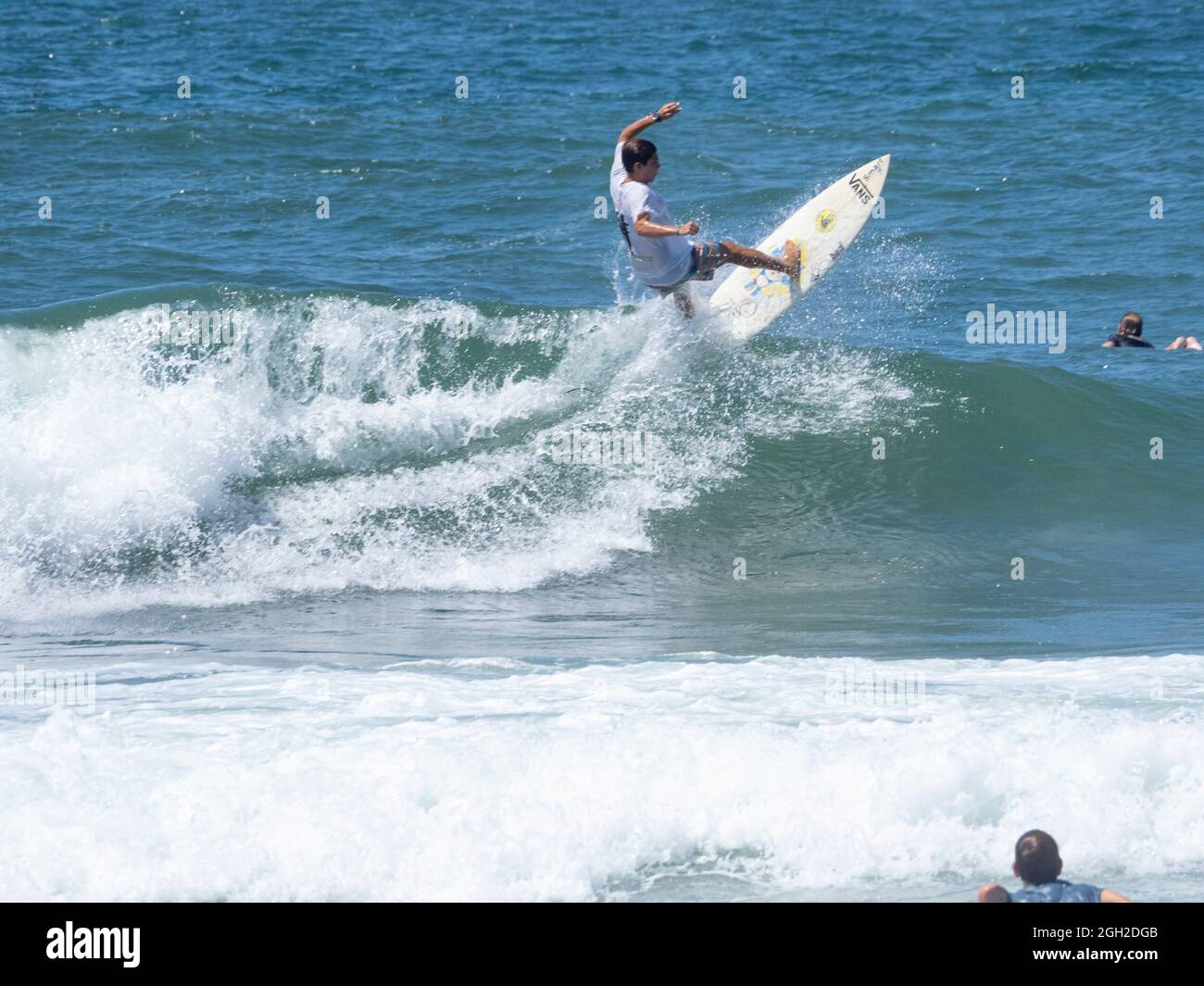 Surfer nehmen Wellen und manövrieren am Meer an einem klaren Sommertag. Stockfoto