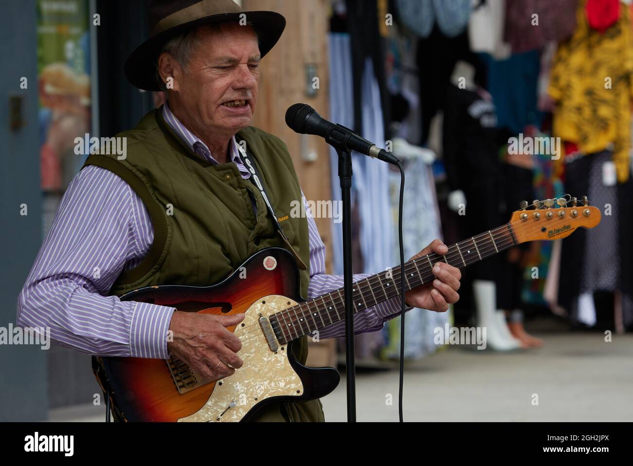 Der Straßenmusiker sah in Bognor Regis singen und Gitarre spielen. Stockfoto