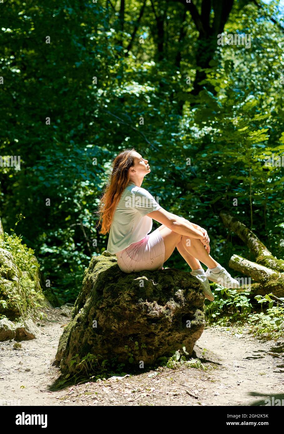 Kind blondes Mädchen sitzt auf einem Felsen am Fluss Sommer Sonnenlicht Stockfoto