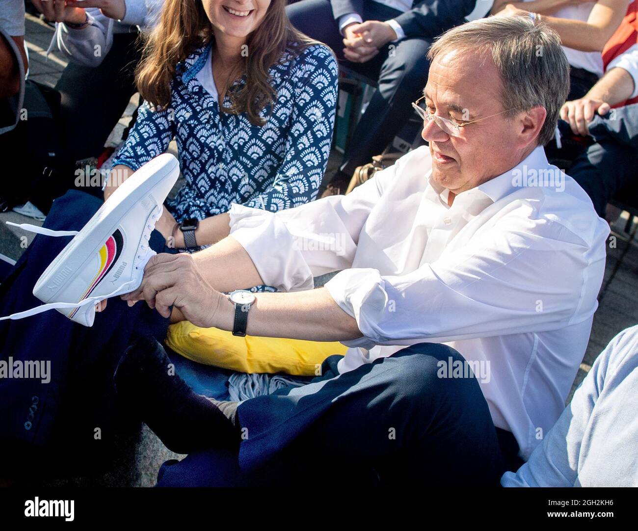 Hannover, Deutschland. September 2021. Armin Laschet (m), Kanzlerkandidat der CDU/CSU und Vorsitzender der CDU, zieht bei einer Wahlkampfveranstaltung der Jungen Union (JU) ein Paar Schuhe mit Streifen in Schwarz, Rot und Gold an, Die er zuvor von Tilman Kuban (r), Bundesvorsitzender der Jungen Union, erhalten hatte. In einer Wahlkampfarena in Hannover stellte sich Laschet Fragen der Jungen Union. Wiederholung mit unterschiedlichen Bilddetails Quelle: Hauke-Christian Dittrich/dpa/Alamy Live News Stockfoto