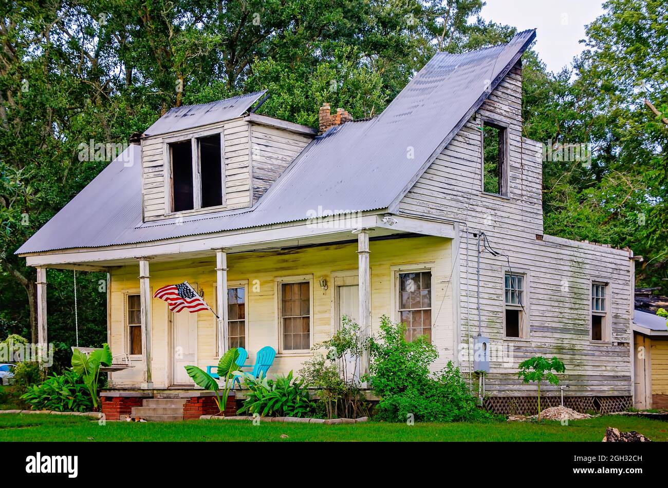 Eine amerikanische Flagge fliegt am 31. August 2021 in Bayou La Batre, Alabama, auf ein feuerbeschädigtes Haus. Das Haus im Creole Plantation-Stil wird gerade renoviert. Stockfoto