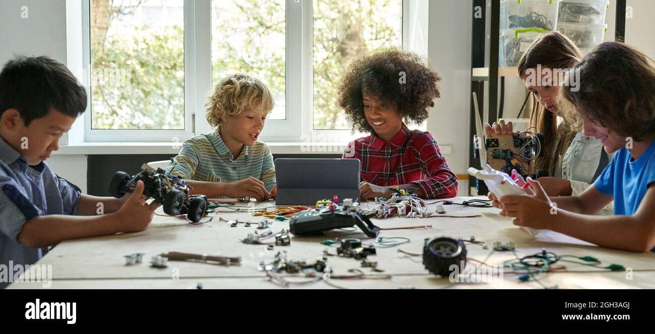 Multirassische Schüler Schüler, die mithilfe eines Tablet-Computers Roboterautos herstellen. Stockfoto