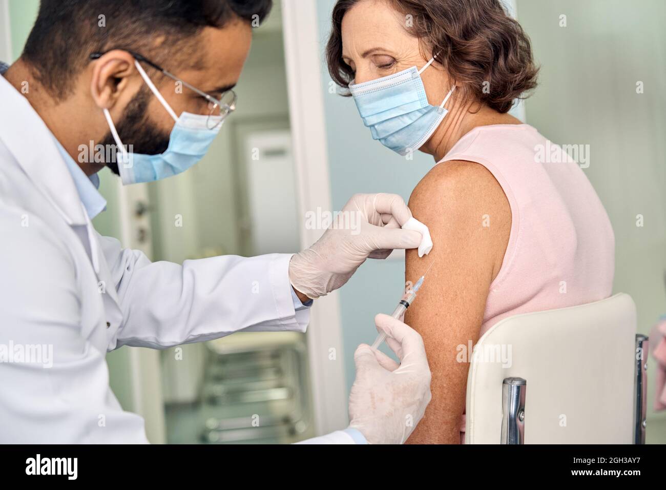Ältere ältere Frau, die Gesichtsmaske trägt und Impfungen erhält. Stockfoto