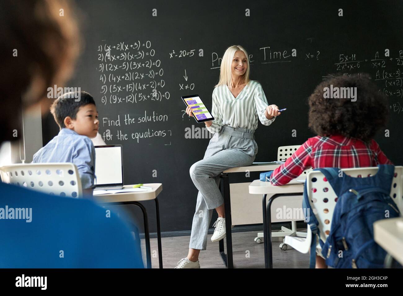 Lehrer, der Schüler in der Matheklasse mit einem digitalen Tablet im Klassenzimmer unterrichtet. Stockfoto