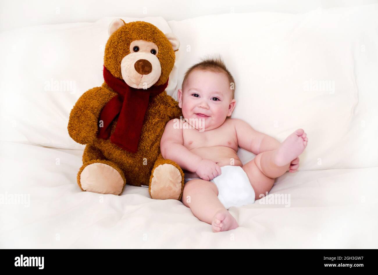 Lächelnder molliger Junge sitzt neben einem gefüllten Teddybär Stockfoto