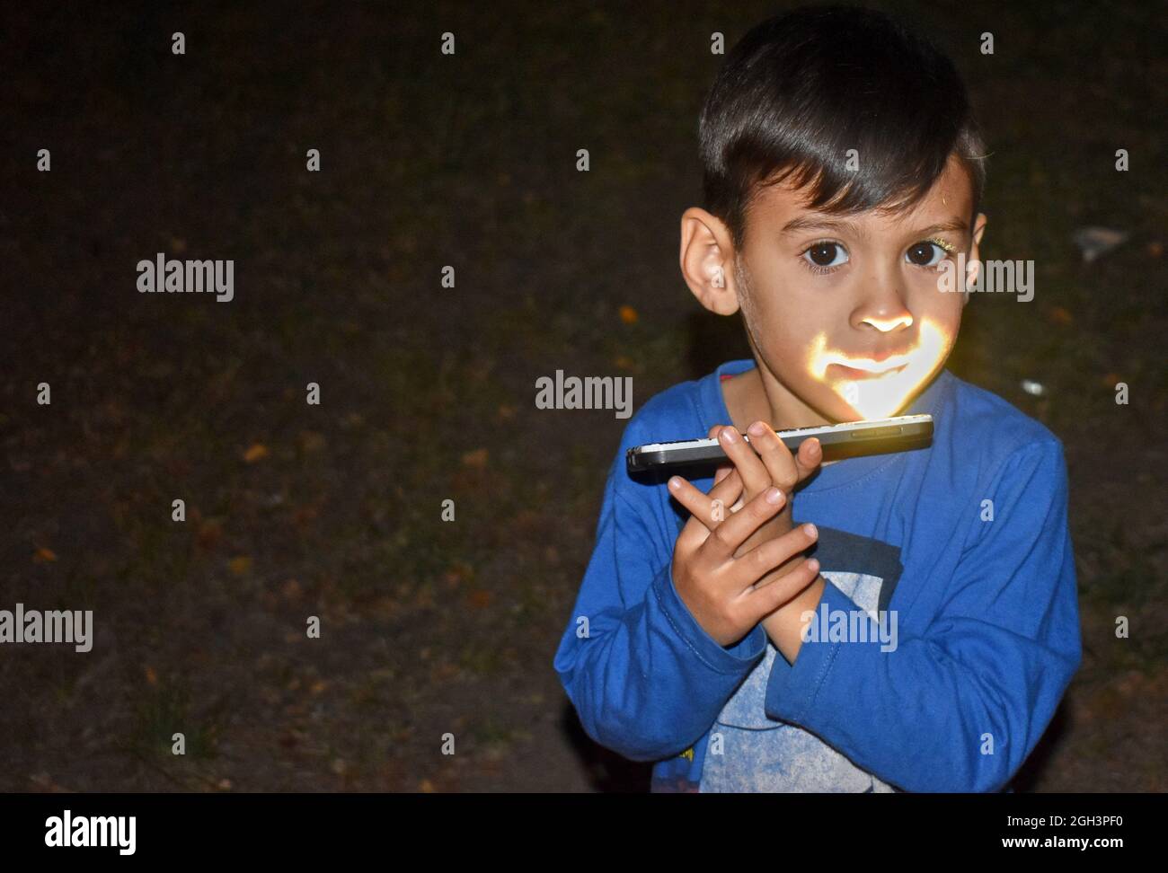 latino Junge beleuchtet sein Gesicht mit einem Smartphone von unten. Horizontal. Speicherplatz kopieren Stockfoto