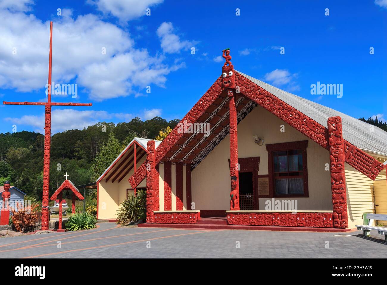 Whakarewarewa Maori Village, Rotorua, Neuseeland. Die Wharenui (Versammlungshaus) und Pou haki (Fahnenmast), beide mit traditionellen Schnitzereien bedeckt Stockfoto
