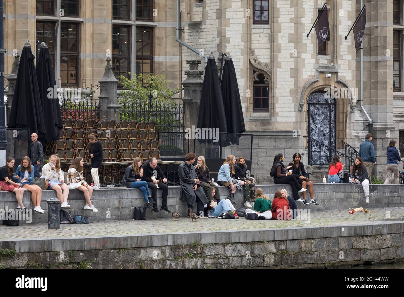 Studenten und Jugendliche entspannen sich am Fluss Leie, in der Innenstadt der historischen Stadt Gent, Belgien Stockfoto