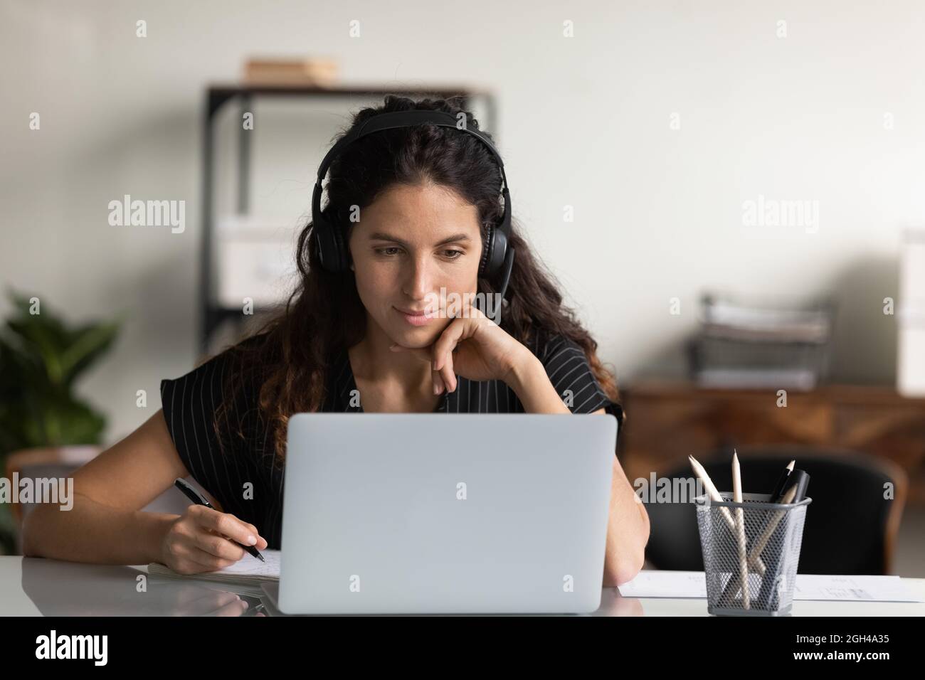 Fokussierte Erwachsene Studentin in Kopfhörern mit Laptop Stockfoto
