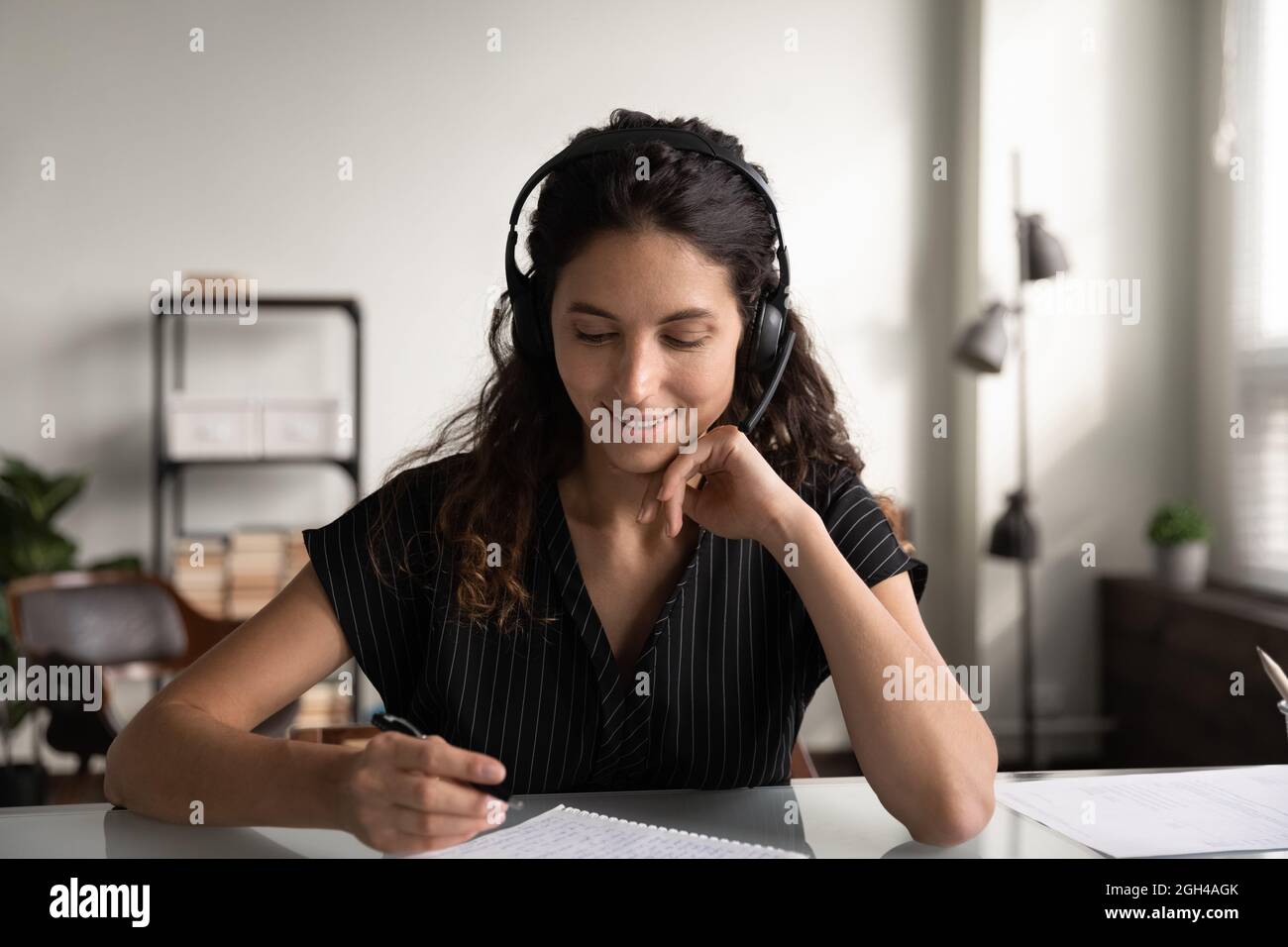 Fröhlicher Student mit Kopfhörern, der Webinar hört Stockfoto