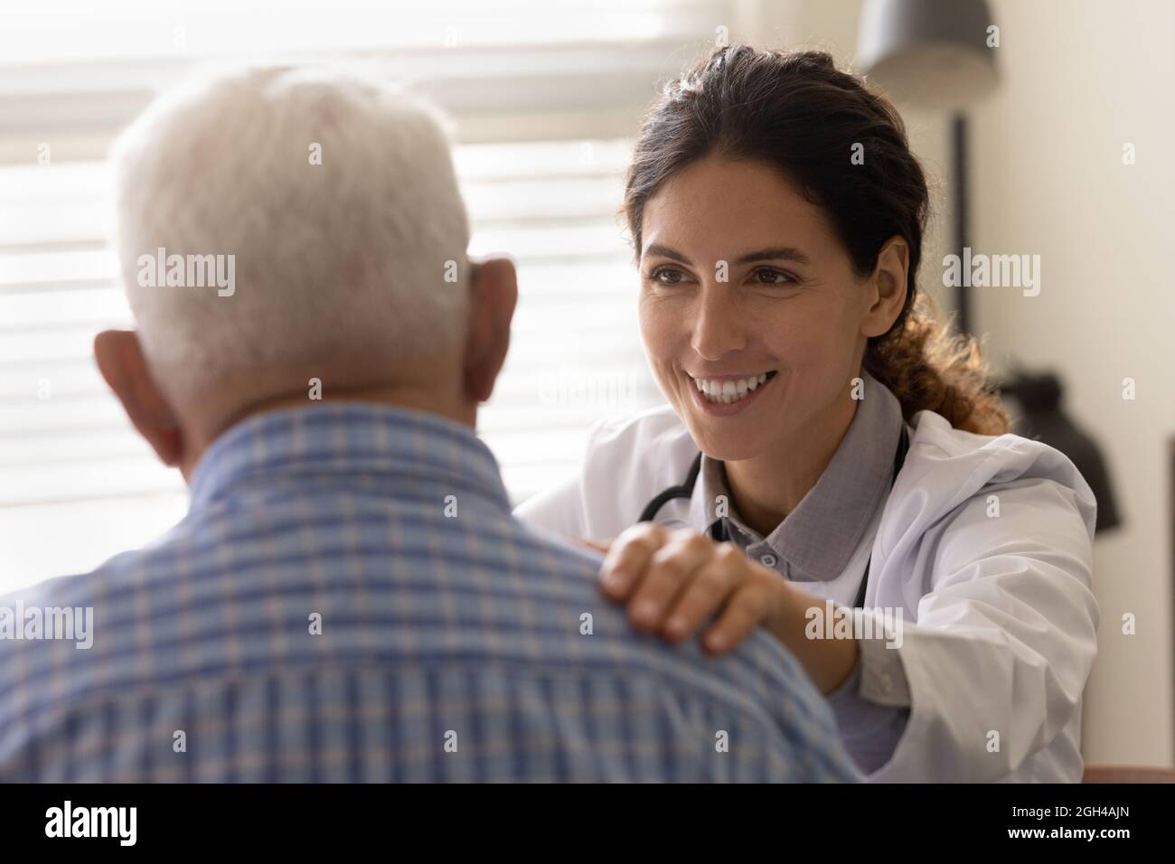 Glücklicher Hausarzt, der den älteren Patienten Hoffnung und Unterstützung gibt Stockfoto