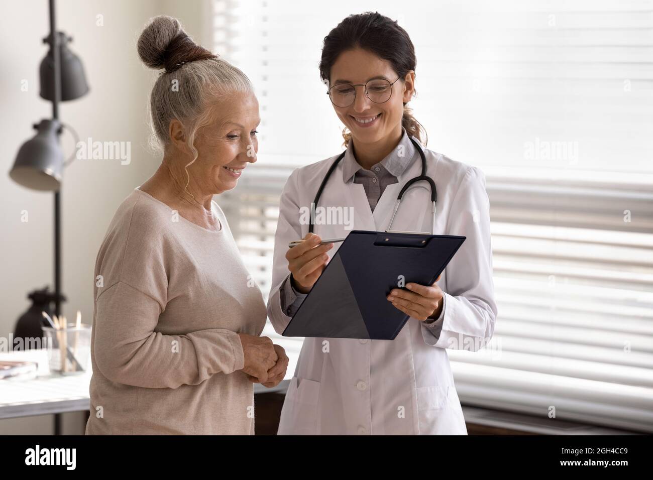 Glücklicher GP-Therapeut zeigt Pad zu reifen 70er Jahre weibliche Patientin Stockfoto