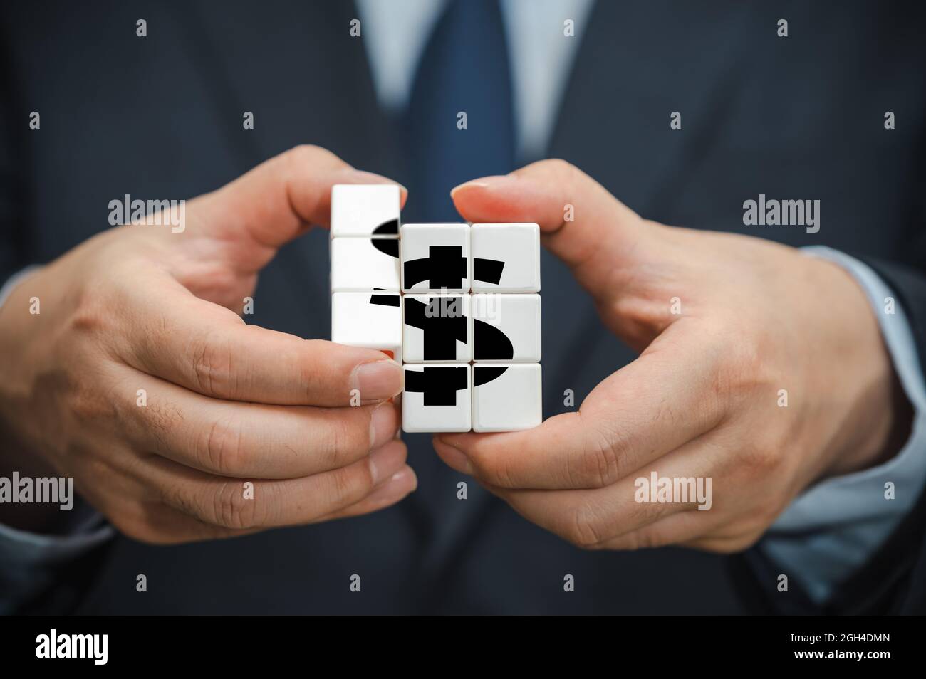 Hände eines Geschäftsmannes, der einen Würfel mit einem Symbol für die Dollaranzeige hält. Stockfoto