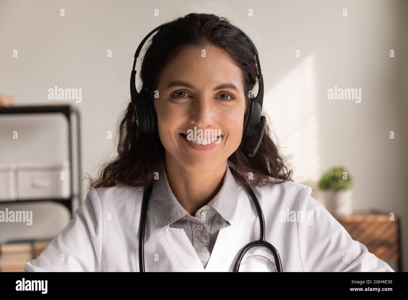 Glücklicher Hausarzt in Kopfhörern, der Online-Hilfe gibt Stockfoto
