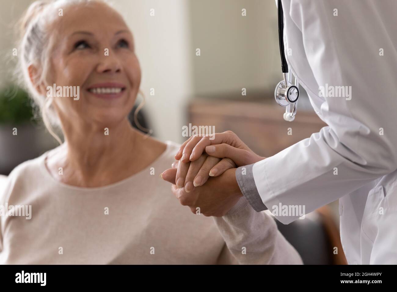 Glückliche ältere Frau, die einen Arzt besucht und optimistische Nachrichten erhält Stockfoto