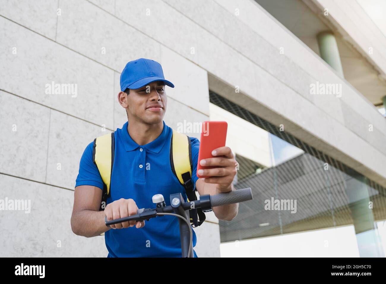 Kurier Mann tun Fast-Food-Lieferservice mit Handy und Elektroroller - liefern Transport Geschäftskonzept - Fokus auf Gesicht Stockfoto